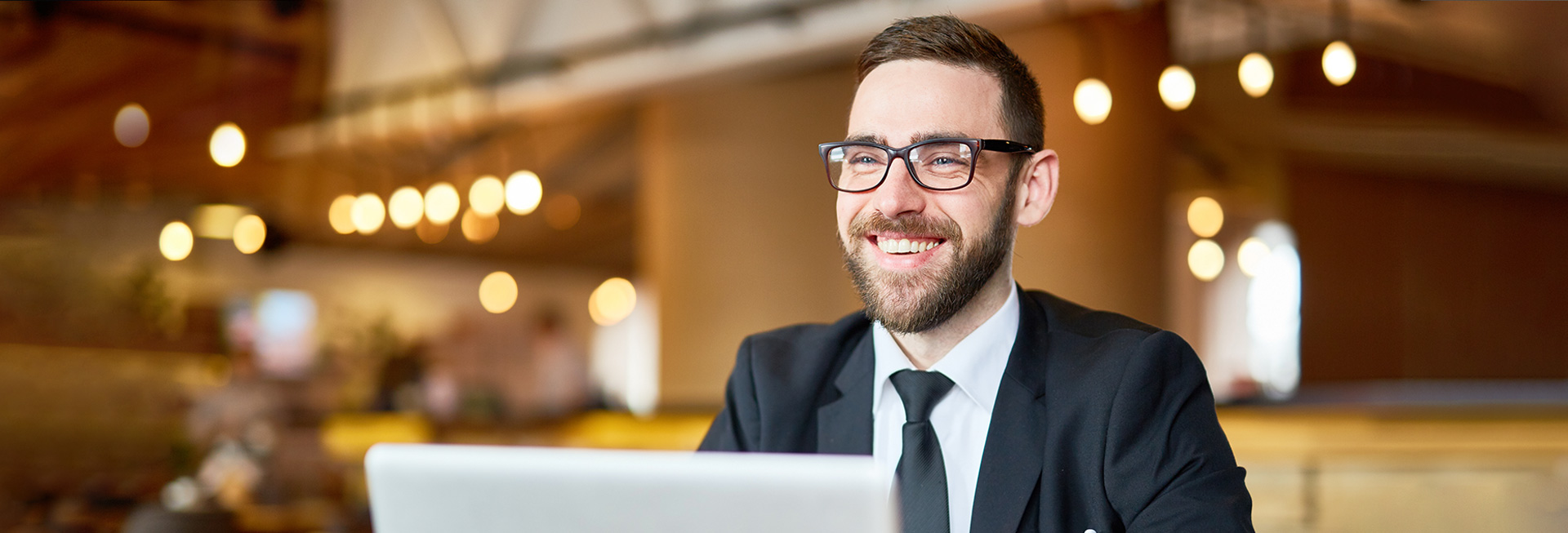 Posh businessman in elegant suit sitting in front of laptop and searching in the net